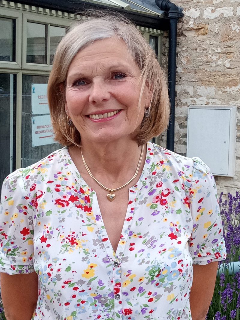 Portrait image of Cathey, Trustee, smiling in front of Churn building