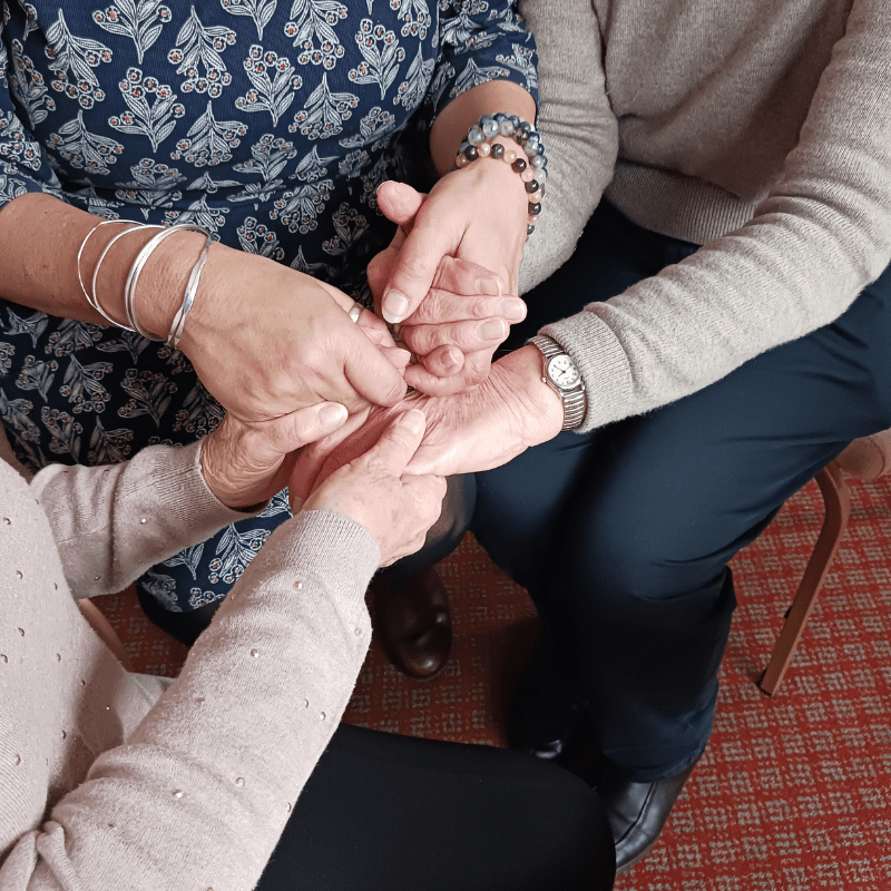 Three people sat down holding hands