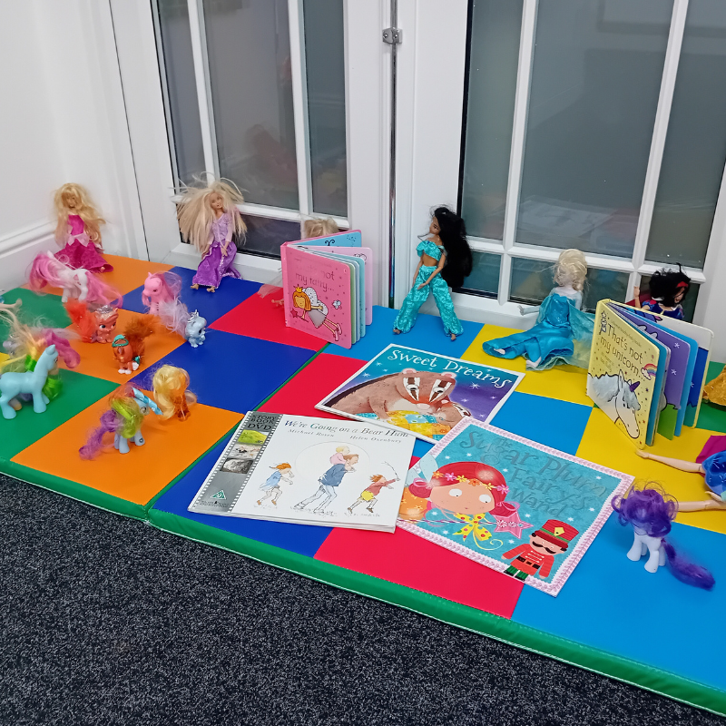 Room set up with soft play mats with children's reading books and dolls
