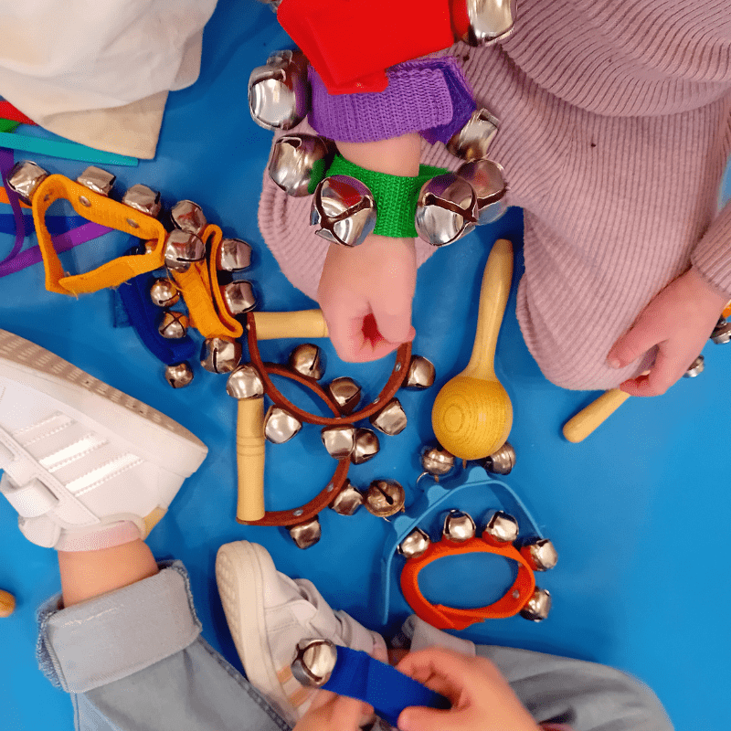 Two young children sat down on the carpet playing with toy musical instruments